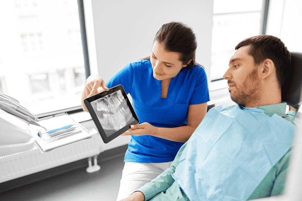 Dentist using a tablet to show patient x-rays of teeth