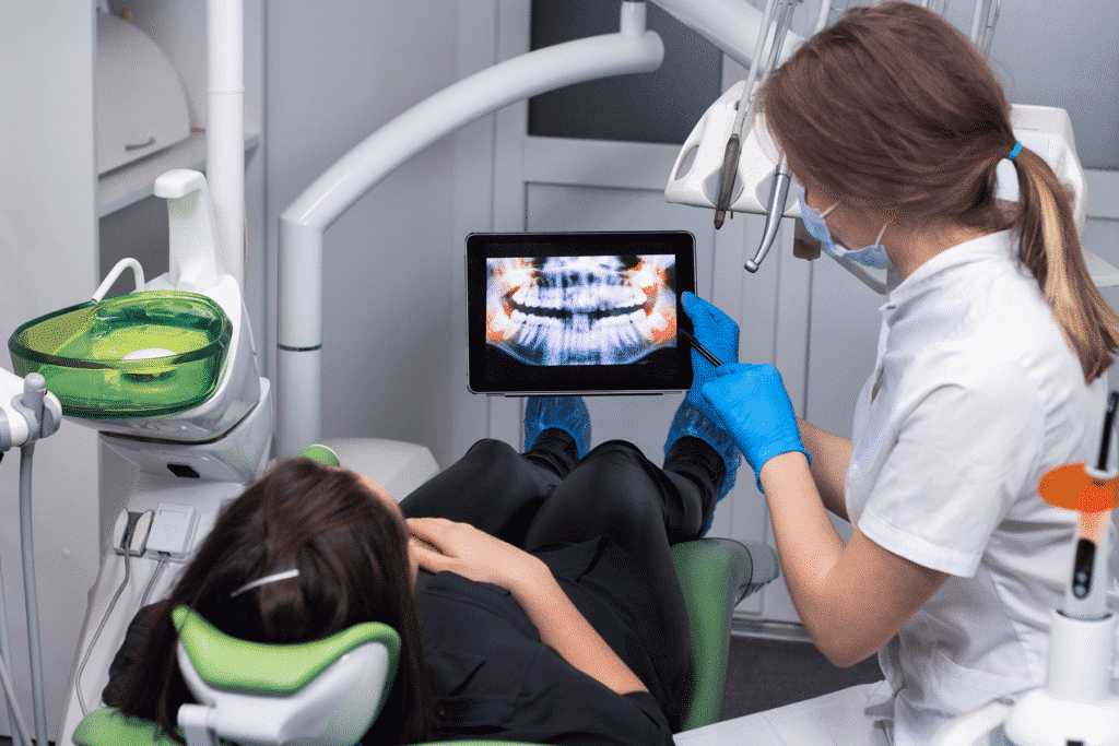 Dentist showing patient teeth x-rays on panel pc