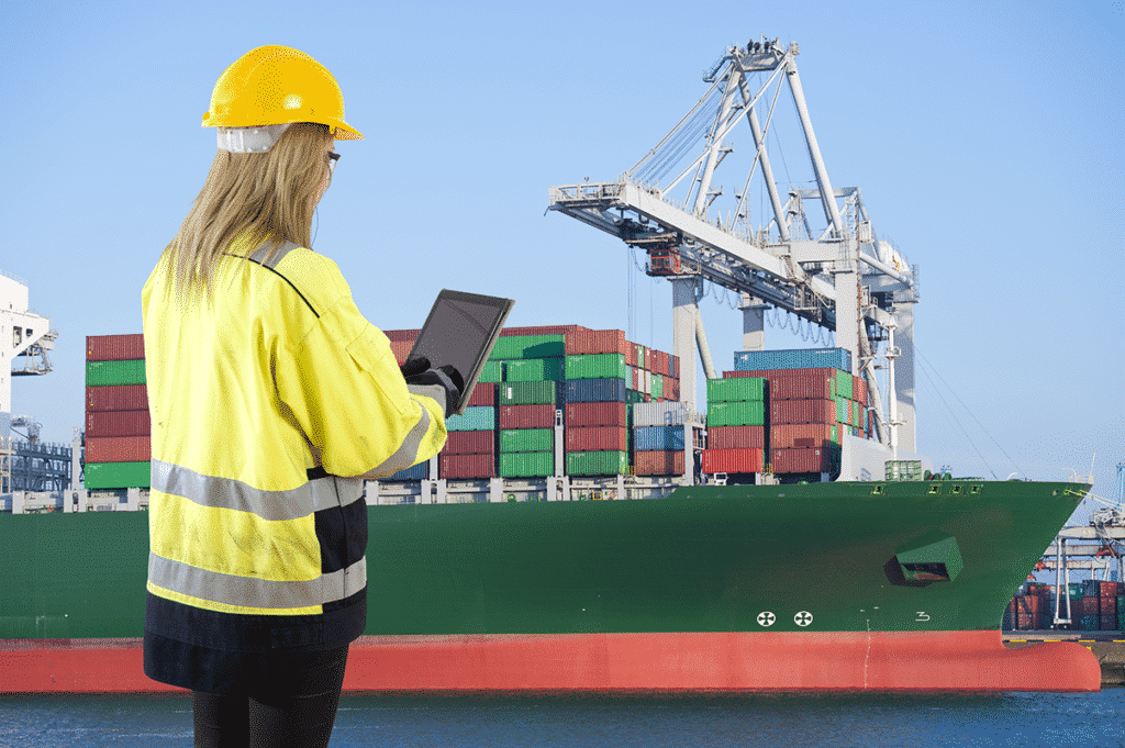 Shipping dock worker using a tablet to connect to equipment and track containers